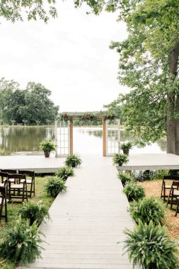 Açık havada, göl kenarında kemer ve yeşillik ile yapılan bir düğün töreni..