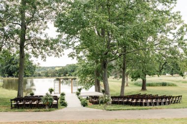 Açık havada, sandalyeler ve göl kenarındaki kemerle yapılan düğün töreni..