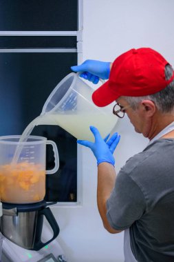 Şef blender 'a doğranmış meyve dolduruyor.