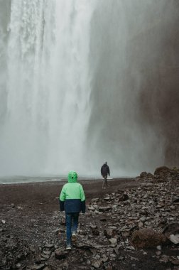 Oğlan ve baba Skogafoss Şelalesinde, İzlanda, sisli ve görkemli bir manzara