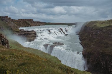 Güçlü Gullfoss şelalesi bulutlu bir gün, yeşil çimen, altın çember