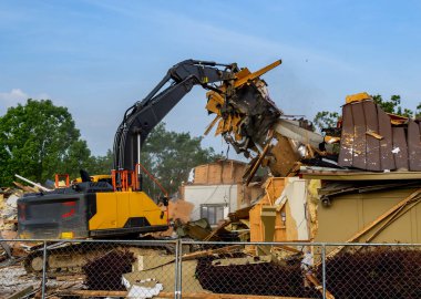 Büyük bir kazı makinesi kullanılmayan bir binayı yıkıyor..