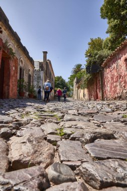 tourists walking on historical cobblestone street in colonia clipart