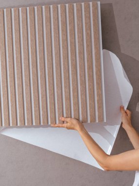 Bir kız apartmanın duvarına inşaat panelleri yapıştırıyor.