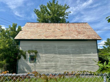 Vermont 'ta mavi gökyüzünün altında yeşilliklerle çevrili yıpranmış beyaz bir kulübe.