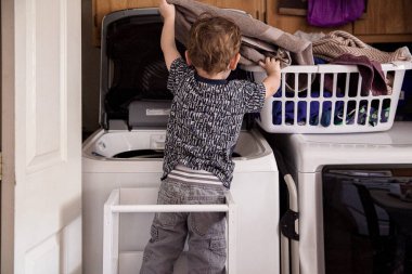 Bebek çamaşırları çamaşır odasında çamaşır makinesine yüklüyor.