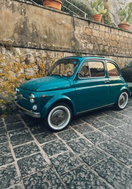 Tuğla kaldırıma park etmiş mavi bir Fiat