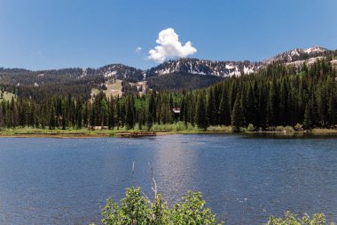 Güneşli gökyüzünün altında, sakin bir göl.
