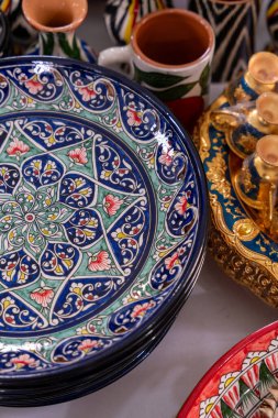 Çiçek desenli mavi bir tabak diğer tabaklarla birlikte bir masada oturur.