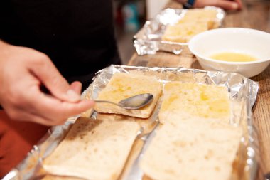 Erimiş tereyağını ekmek dilimlerine döken kişi