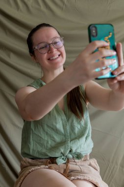 Woman taking a selfie with a smile, wearing glasses, casual dress clipart