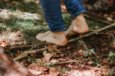 Yapraklar, dallar ve yeşilliklerle ormanda yalınayak yürüyor.