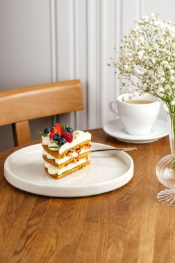 Beyaz tabakta bir parça kek, fincanda çay.