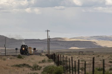 A steam engine in the distance going through a prairie clipart