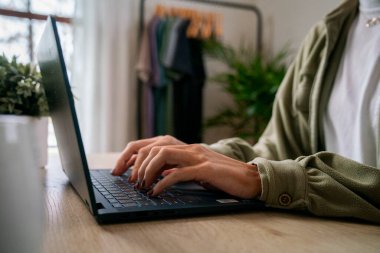 Tahta bir masada dizüstü bilgisayarda çalışan biri.