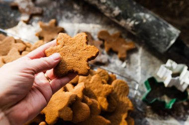 Hand holding a freshly baked gingerbread cookie over a cooling rack clipart