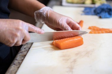 Suşi şefi tezgahta çiğ somon keser.