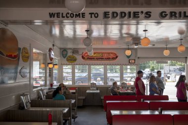 İç koltuklar ve yol kenarındaki lokantada bekleyen insanlar.