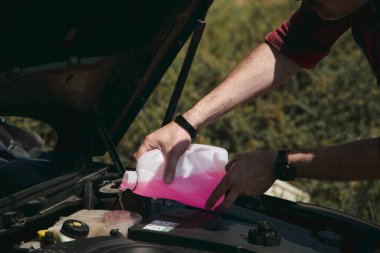 Genç adam araba tamir ediyor.