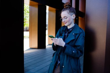 Gözlüklü kız cep telefonuna mesaj yazıyor.