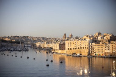 Güneş doğarken Valletta Limanı 'nda köpüklü deniz ve tarihi binalarla.