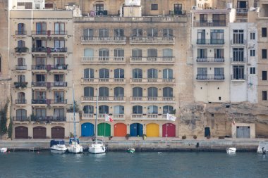 Taştan mimarisi ve renkli kapıları olan Valletta limanının görüntüsü.