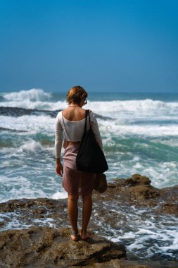 Sahilde duran bir kadın yolcu..
