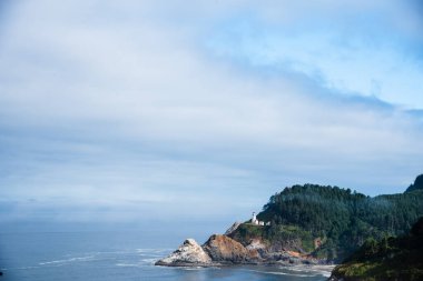 Distant view of Heceta Head Lighthouse on Oregons rugged coastline.  clipart