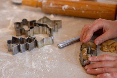 Tatil temalı kurabiye kesicilerle kurabiye hamuru bastıran eller