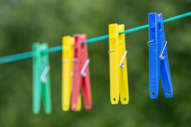 Plastic Colourful clothes pegs on a washing line clipart