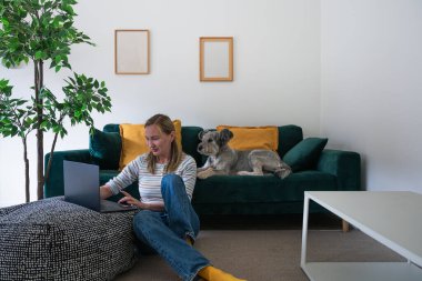 Evde köpeğiyle dizüstü bilgisayarda çalışan serbest çalışan bir kadın.