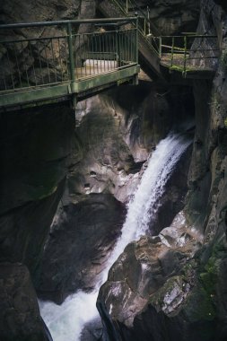 Waterfall below the mossy suspended walkway in a ravine clipart