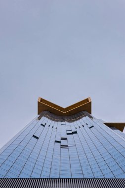 Aşağıdan yansıtıcı cam ve keskin açılarla çekilmiş bir gökdelen.