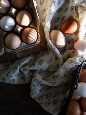 Eggs in a carton and basket on a patterned cloth with soft lighting clipart