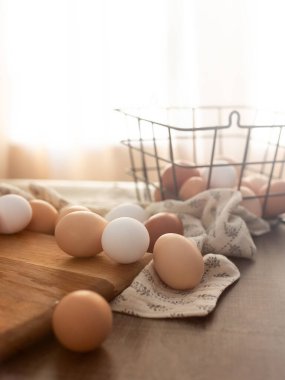 Eggs on a cutting board and wire basket in soft, warm lighting clipart