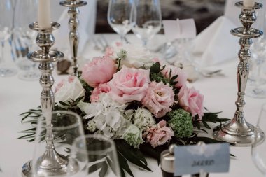 Pembe gülleri ve gümüş mum tutacağı olan zarif bir düğün süsü..