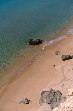 View of sandy beach Prainha Das Pocasby from cliff, among the rocks. clipart