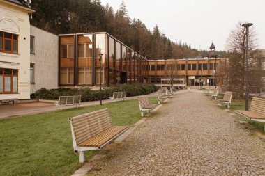 Boş banklar, cam cepheli modern binaya doğru gidiyor.