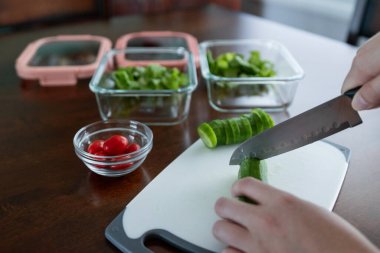 Yemek hazırlamak için salatalık kesen kişi