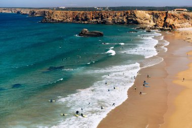 Praia do Tonel in Sagres, Algarve, Portekiz 'deki dalgalarda sörfçüler.