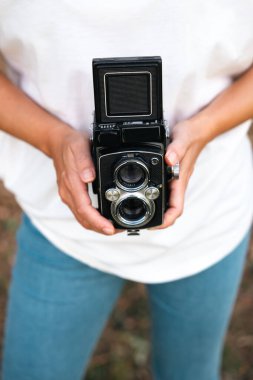 A woman's hands holding an analog medium format camera. clipart