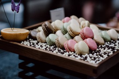 Dekoratif elementlerle açık büfe tepsisinde gösterilen renkli kurabiyeler.