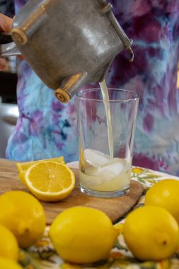 Limon suyu, yanında dilimlenmiş limonlarla bir bardağa sıkıştırılıyor.