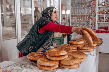 Bir kadın markette ekmek satıyor.