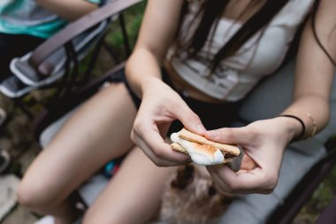 Genç bir kadın açık hava toplantısında kızarmış s 'more hazırlıyor.