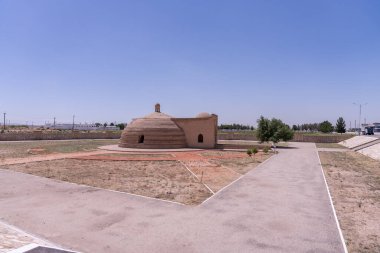 Tepesinde kubbe olan küçük bir bina bir tarlada duruyor.