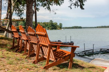 Kıyıda göle bakan Adirondack sandalyeleri