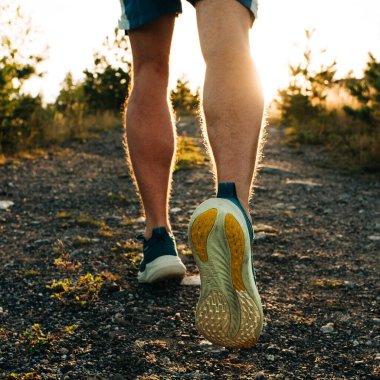 Adamın bacakları gün batımında tepeye koşmaya hazır.