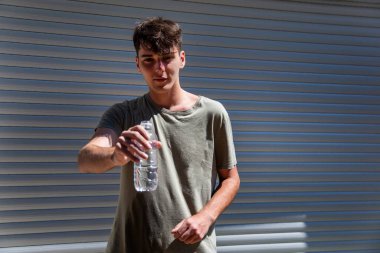 Young handsome man extends a hand with bottle of water clipart