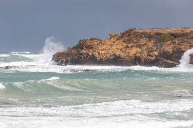 Warrnambool 'daki turuncu engebeli kayalıklara çarpan dalgalar